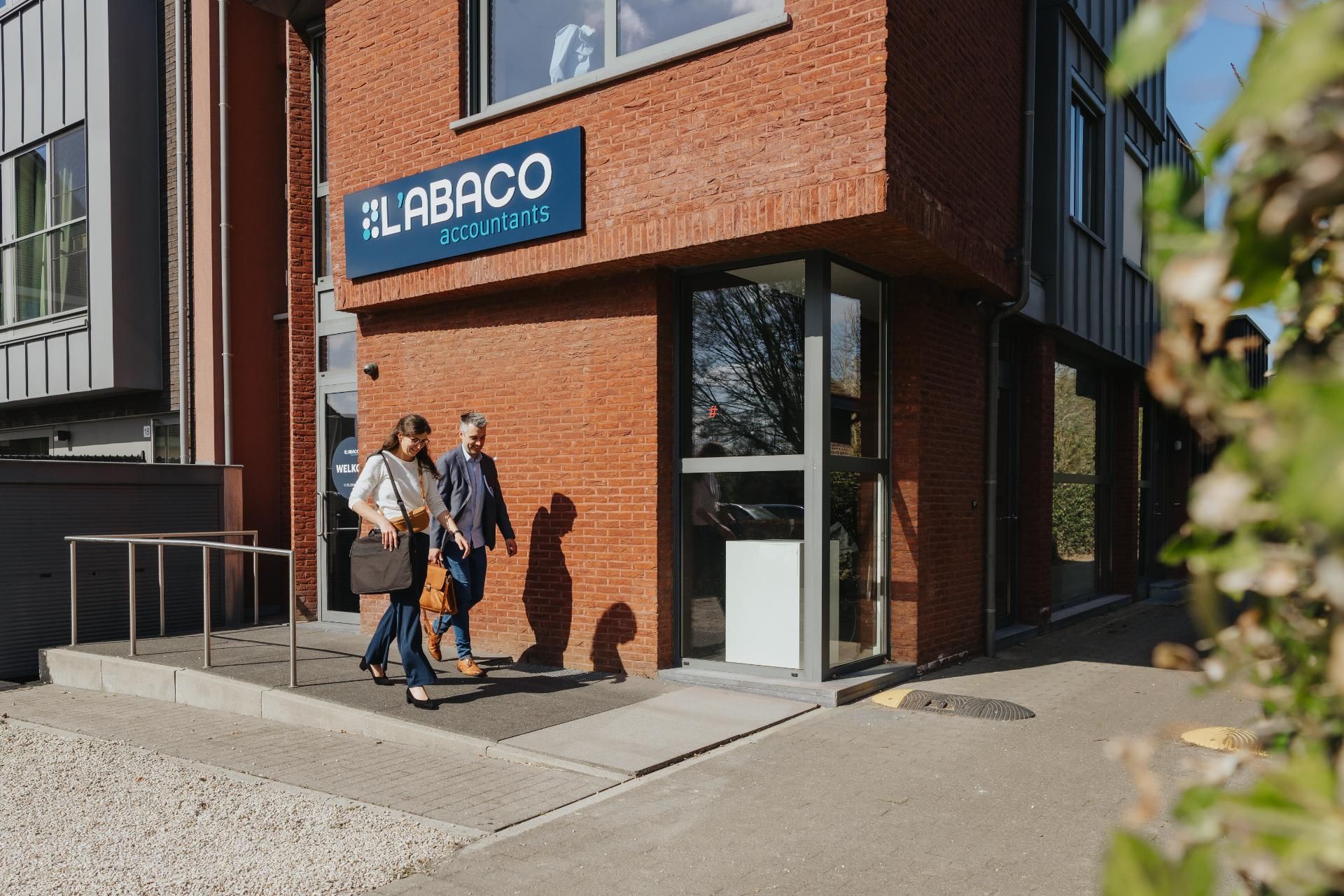 Twee medewerkers van L'Abaco accountants verlaten het kantoor in zonlicht, familiebedrijf sinds 1992